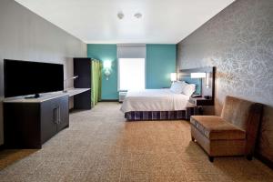 a hotel room with a bed and a tv and a chair at Home2 Suites By Hilton El Reno in El Reno