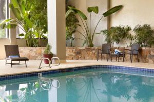 a swimming pool with chairs and plants in a building at Embassy Suites by Hilton Oklahoma City Will Rogers Airport in Oklahoma City