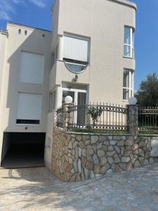 a house with a stone wall and a fence at Apartment Ajdarpasic in Bar