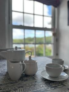 a table with cups and tea pots on a table at The Boathouse in Golant
