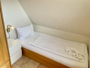 un piccolo letto con lenzuola bianche e un cuscino di Andersen OG a Westerland