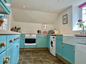 a kitchen with blue cabinets and a washer and dryer at The Boathouse in Golant