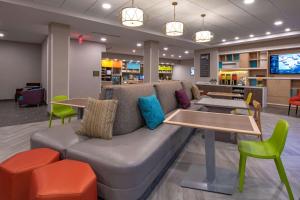 a couch in a waiting room with a table and chairs at Home2 Suites by Hilton Omaha I-80 at 72nd Street, NE in Omaha