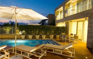a pool with chairs and an umbrella next to a building at Villa Oleander in Petrcane