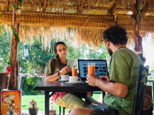 a man and a woman sitting at a table with a laptop at Dolape Villa in Ella