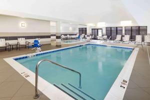 a large swimming pool in a building with chairs and tables at Homewood Suites by Hilton Munster in Munster