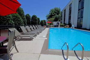 a swimming pool with chairs and a red umbrella at Hampton Inn Norfolk/Chesapeake - Greenbrier Area in Chesapeake
