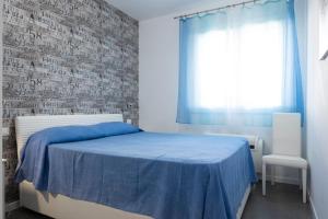 een slaapkamer met een blauw bed en een bakstenen muur bij Casa Mirea di Teti con piscina a Macari in Macari