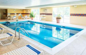 a large swimming pool in a hotel with two chairs at Hampton Inn Gloucester in Gloucester