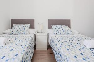 two twin beds in a room with white walls at Algaba Severo Ochoa 1 in La Algaba