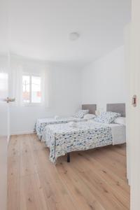 two beds in a white room with a wooden floor at Algaba Severo Ochoa 1 in La Algaba