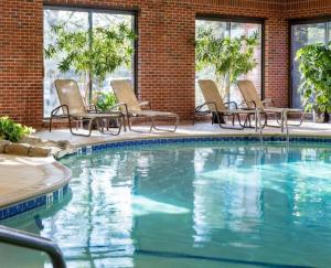 einen Pool mit Stühlen, einem Tisch und einem Gebäude in der Unterkunft Doubletree by Hilton, Leominster in Leominster