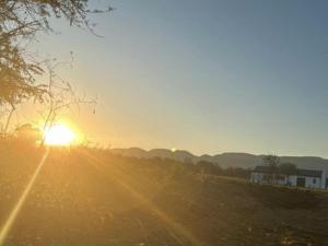 un coucher de soleil au-dessus d'un champ et un coucher de soleil en arrière-plan dans l'établissement Mbhathane Farm Lifestyle and Spa, 