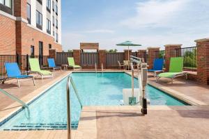 a swimming pool with chairs and an umbrella on a building at Hampton Inn & Suites Norman-Conference Center Area, Ok in Norman