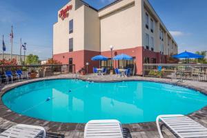 uma piscina em frente a um hotel com cadeiras e guarda-sóis em Hampton Inn Owensboro em Owensboro