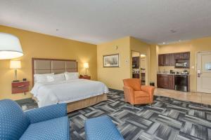オーエンズボロにあるHampton Inn Owensboroのベッド1台と椅子2脚が備わるホテルルームです。