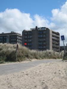 un edificio junto a una playa con un edificio en App KLIF De Panne - top location & sea front !!, en De Panne