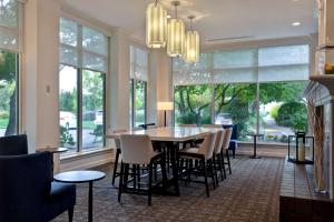 a dining room with a table and chairs and windows at Hilton Garden Inn Portland/Beaverton in Beaverton