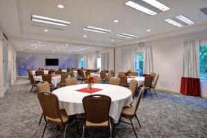 a conference room with tables and chairs and a screen at Hilton Garden Inn Portland/Beaverton in Beaverton