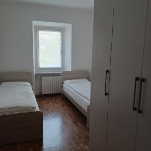 Habitación pequeña con 2 camas y ventana en Federica e Valentina en Brez