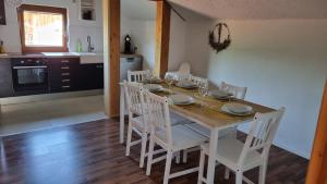 a dining room table with white chairs and a kitchen at Ferienwohnung Bergfreunde in Bergen