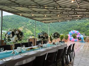 Goga Guest House في كفارياتي: طاولة بيضاء طويلة عليها كراسي وورود
