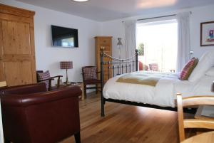 a bedroom with a bed and a chair and a window at Keeper's Lodge in Rowlands Castle