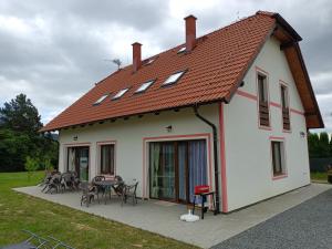 a white house with a roof with a patio at Apartmány u Olšinské kapličky in Horní Planá