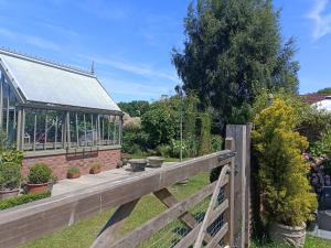 a garden with a wooden fence and a greenhouse at Keeper's Lodge in Rowlands Castle
