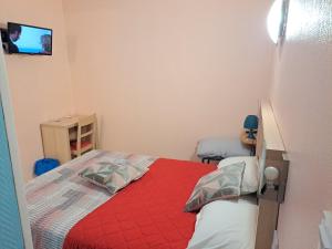 een kleine slaapkamer met een bed met een rode deken bij Hôtel Beauséjour in Nevers