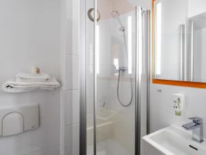 a white bathroom with a shower and a sink at B&B Hotel Hannover-Nord in Hannover