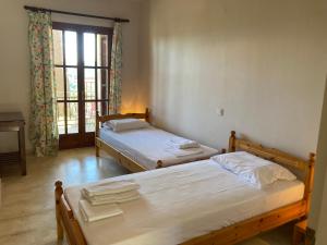 two beds in a room with a window at Kokkini Peach Budget in Kokkínion