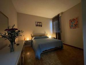 1 dormitorio con 1 cama y 1 mesa con flores en Margherita lake view Apartment, en Ispra