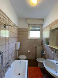 łazienka z 2 toaletami, wanną i umywalką w obiekcie Margherita lake view Apartment w mieście Ispra