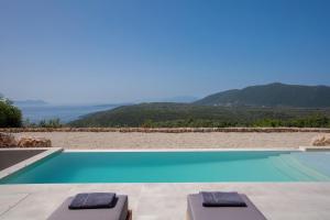 a swimming pool with two lounge chairs and a view at Armante Supreme Villas - Villa Ilianna in Fternón