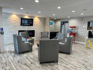 a waiting room with chairs and a fireplace at Clarion Pointe - Greensboro Coliseum Area in Greensboro