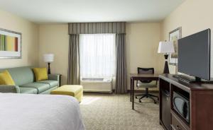 um quarto de hotel com uma cama, um sofá e uma televisão em Hampton Inn & Suites Philadelphia Montgomeryville em North Wales