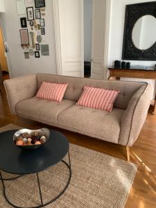 a living room with a couch with two pillows and a table at Escale citadine au centre d'Avignon, climatisation, appartement de charme, spacieux et lumineux in Avignon