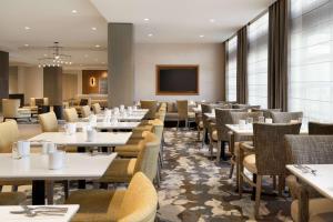 a dining room with tables and chairs and a television at Hilton Garden Inn Newtown Square Radnor in Newtown Square