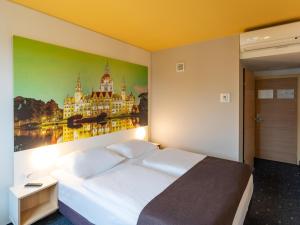 a bedroom with a large white bed with a painting on the wall at B&B Hotel Hannover-Nord in Hannover