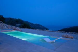 una piscina notturna con una sedia di Armante Supreme Villas - Villa Ilianna a Fternón