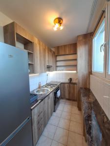 uma cozinha com armários de madeira, um lavatório e uma janela em Kaptár lakás em Komárom
