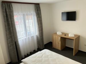 a room with a bed and a window with a telephone at PENSIUNEA KONFORT in Borsa