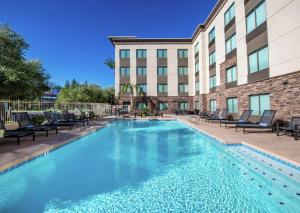 a swimming pool at a hotel with chairs and a building at Hampton Inn Phoenix Airport North in Phoenix