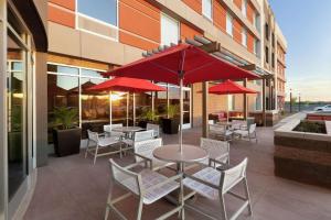 un patio con mesas, sillas y sombrillas rojas en Home2 Suites By Hilton Scottsdale Salt River en Scottsdale