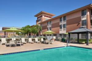 a hotel with a pool and chairs and umbrellas at Hampton Inn Phoenix/Anthem in Anthem