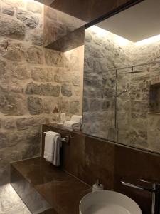 a stone bathroom with a toilet and a glass shower at KAŽIN supreme in Kotor
