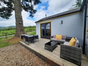 a patio with a couch and a table and a tree at Kinnaird Woodland Lodges in Pitlochry