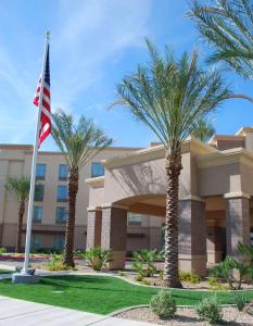 a hotel with palm trees in front of a building at Hampton Inn & Suites Phoenix/Gilbert in Gilbert