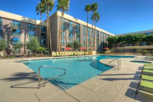 a swimming pool in front of a building with palm trees at DoubleTree by Hilton Phoenix North in Phoenix